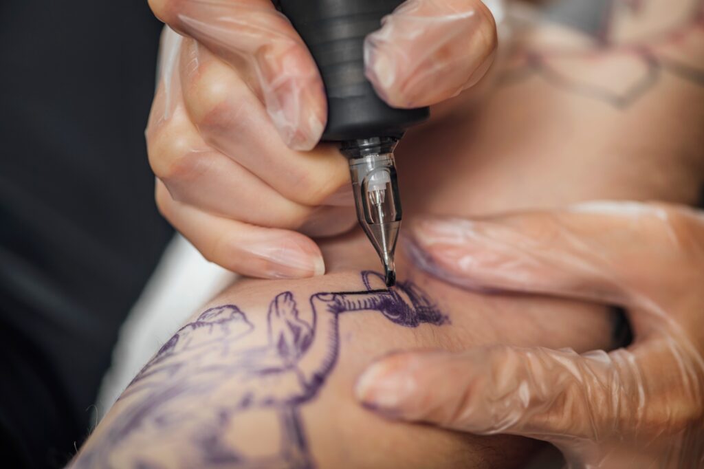 Hand of Tattooist in Rubber Gloves Drawing a Tattoo with Electric Tattoo Gun Close-up