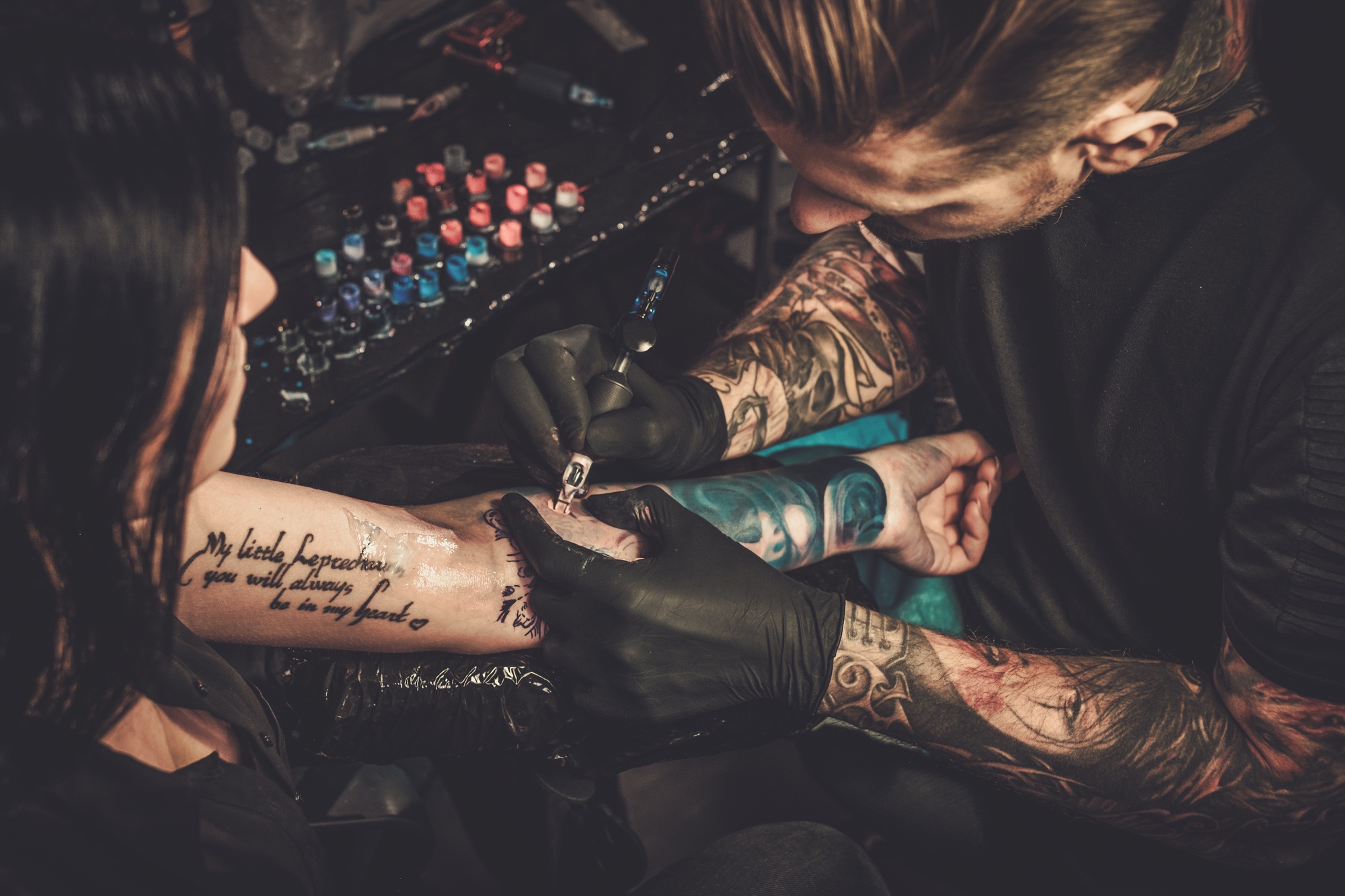 Professional tattoo artist makes a tattoo on a young girl's hand.