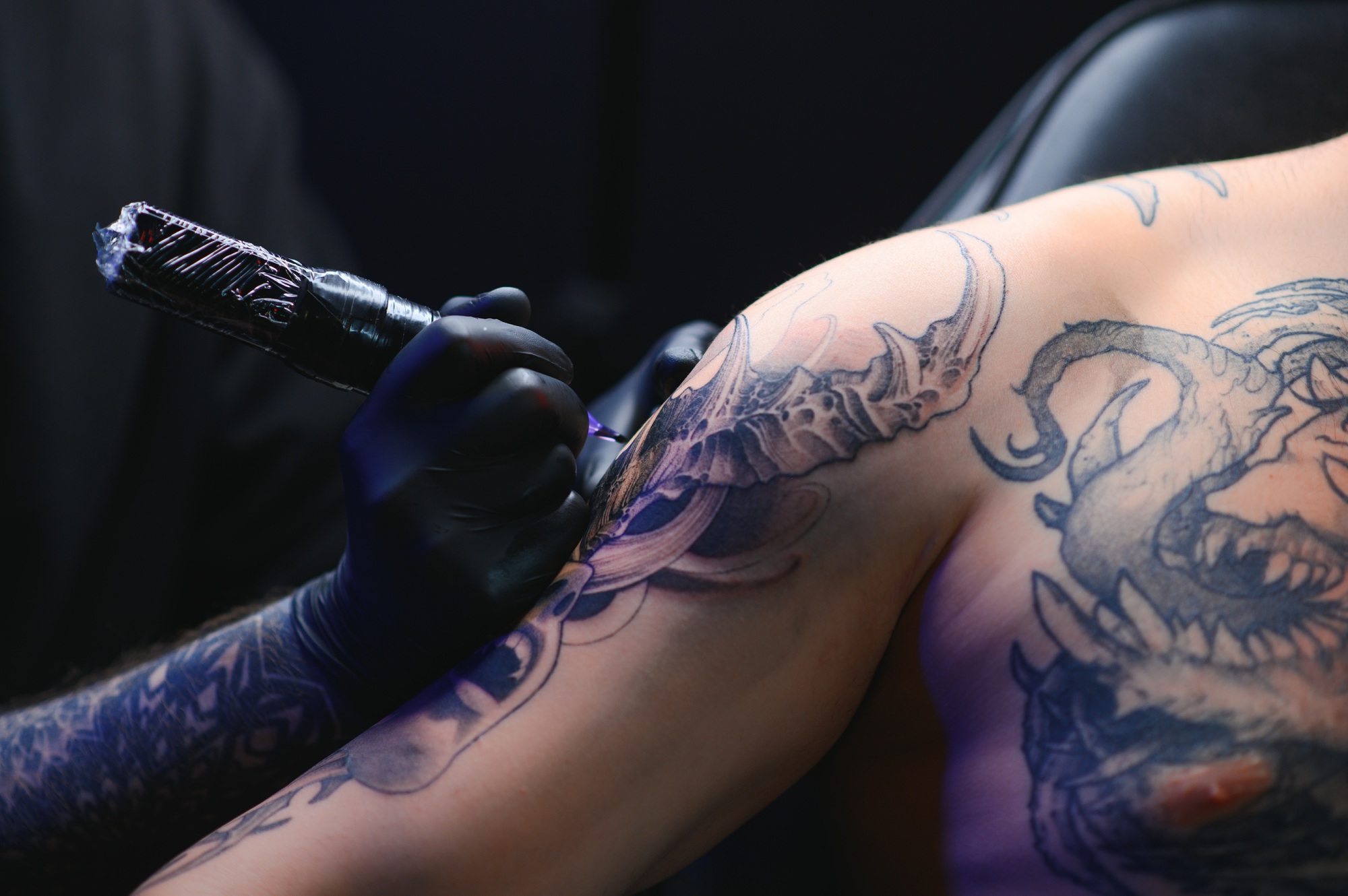 Tattoo artist hands wearing gloves and holding a tattoo machine