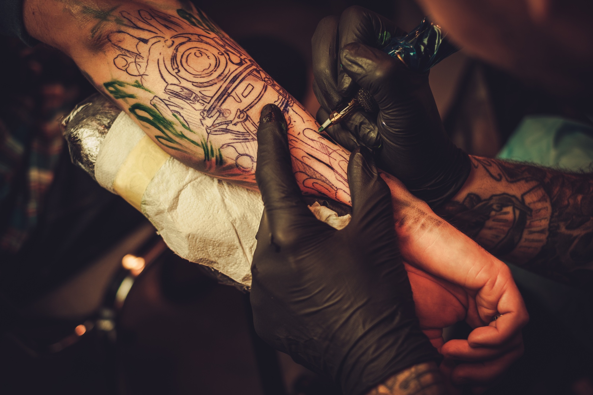Tattoo artist makes a tattoo on a man's hand.