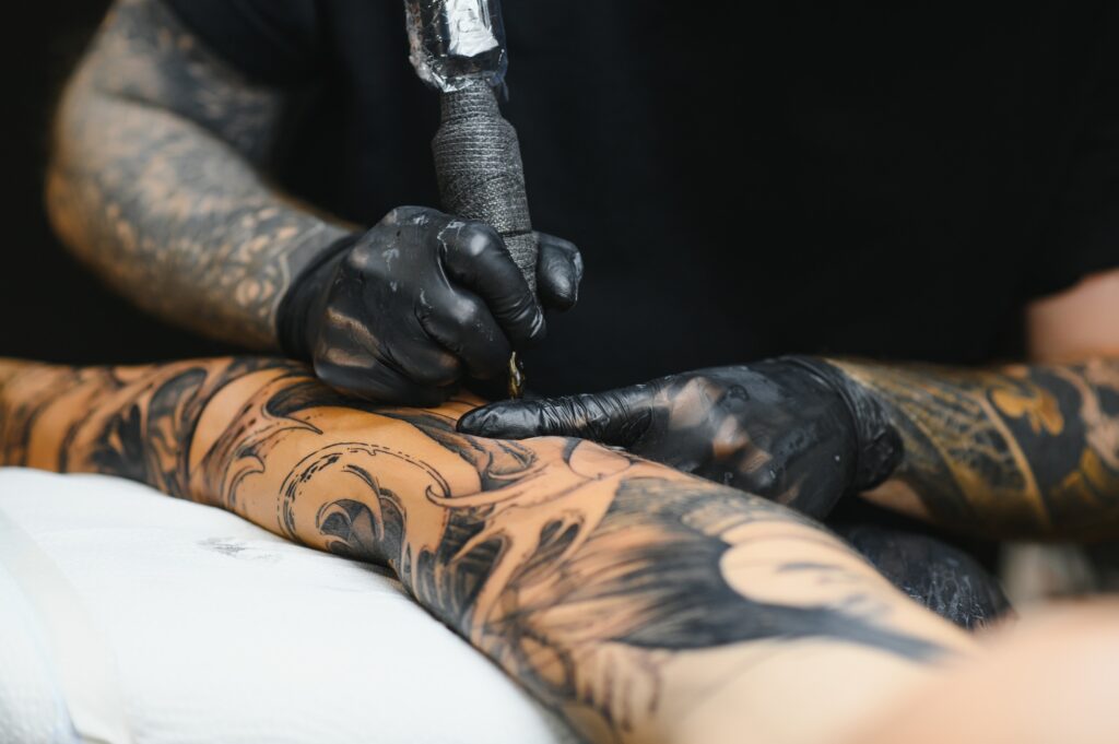 Tattoo salon. The tattoo master is tattooing a man. Tattoo machine, safety and hygiene at work.