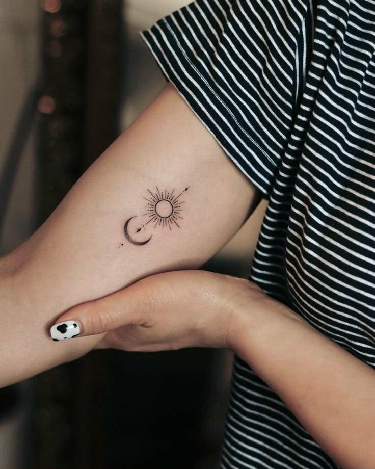 Lille sol- og maane-tatovering paa underarm